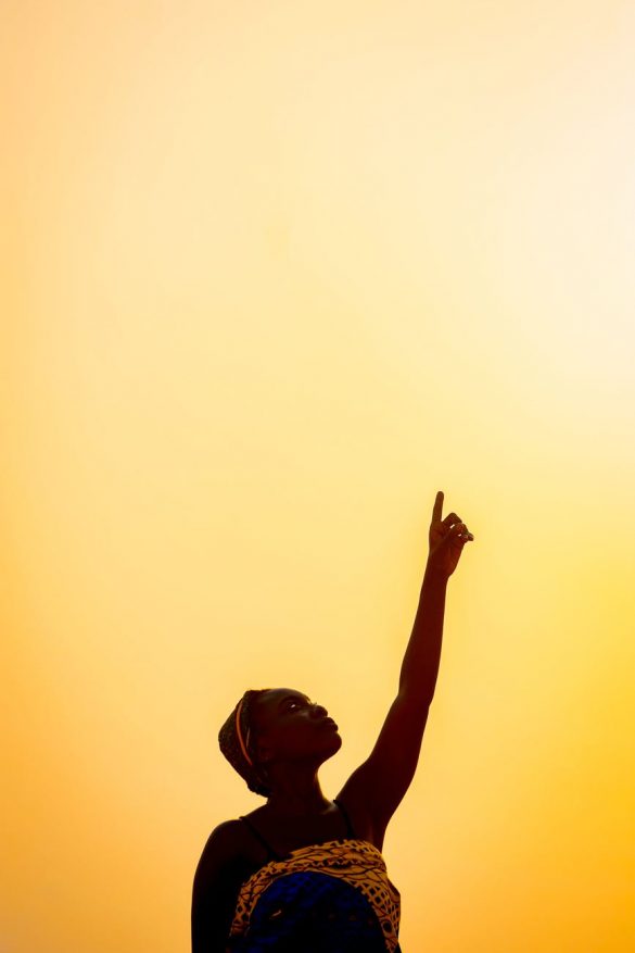 black woman raising hand against skyline