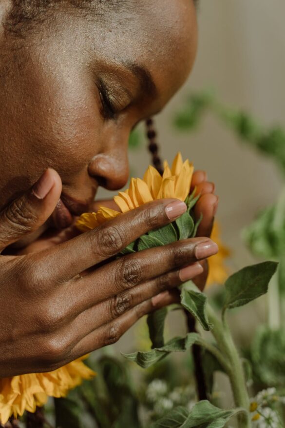 close up photo of a woman smelling a yellow flower