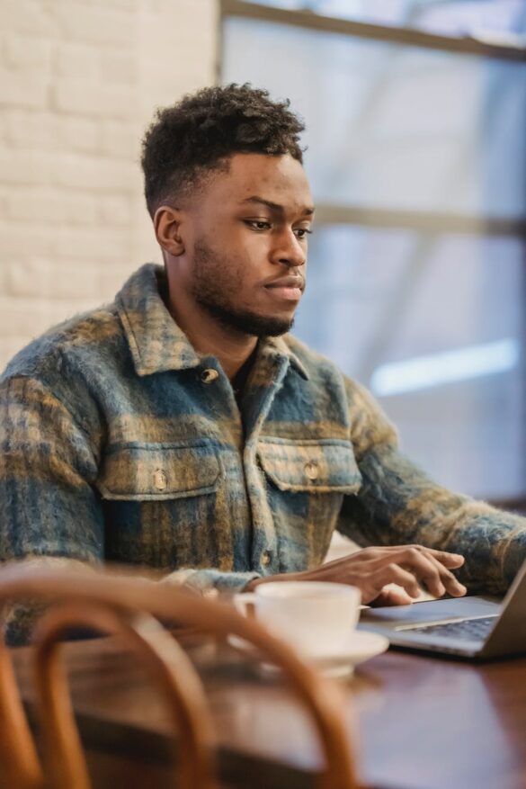 serious black man working on laptop at wooden table