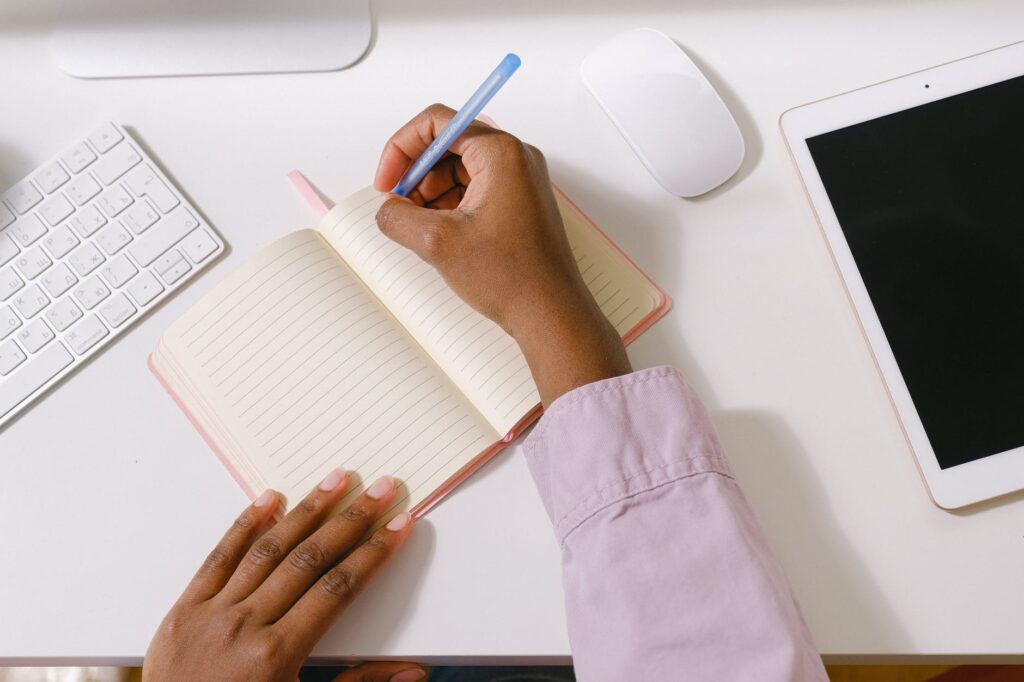 black woman with pen taking notes in planner